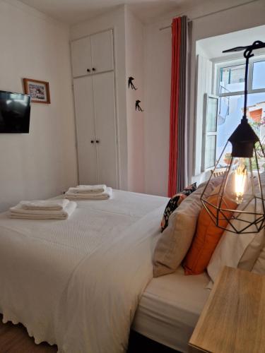 a bedroom with a white bed with a window at Bea's Bed & Breakfast in Tavira