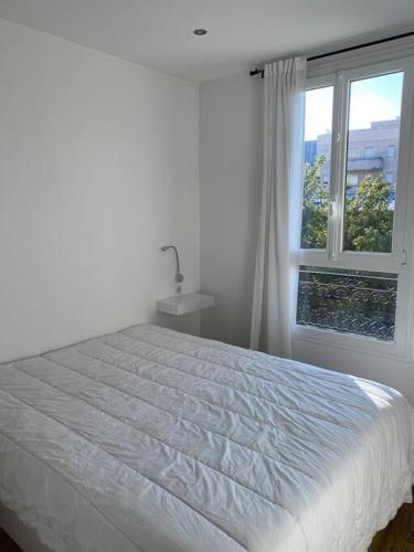 ein weißes Schlafzimmer mit einem Bett und einem Fenster in der Unterkunft Beau 2 pièces - Mairie de Clichy in Clichy