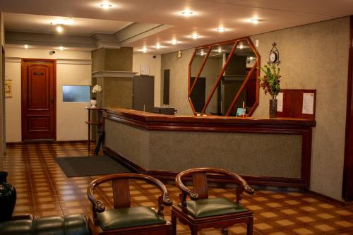 een lobby met een bar met 2 stoelen en een spiegel bij Hotel Aurora in Olímpia