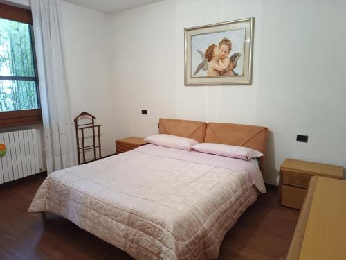 - une chambre avec un lit et une photo sur le mur dans l'établissement Signorile quadrilocale nel verde di Villa Guardia, à Villa Guardia