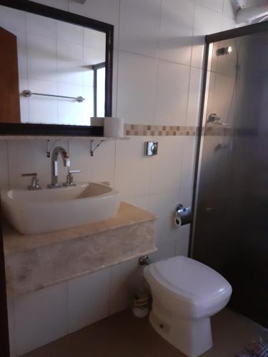 a bathroom with a sink and a toilet and a mirror at Casa/chale Campos do Jordao in Campos do Jordão