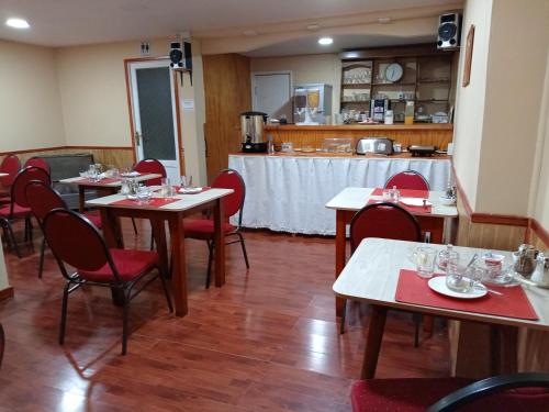 a restaurant with tables and red chairs and a counter at Hostal Reymar in Puerto Natales
