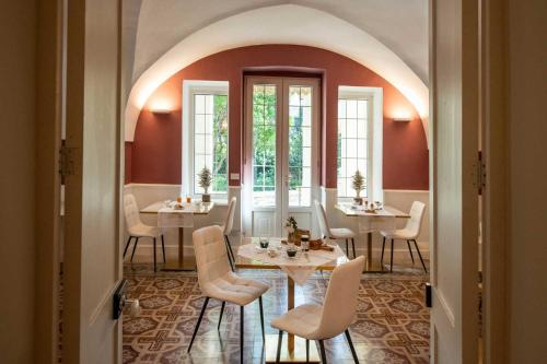 a dining room with white chairs and tables and windows at Palazzo Bove 2 - Villa Dagmar in Galatone