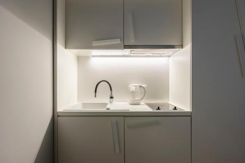 a kitchen with white cabinets and a sink at Chełmońskiego 8-03 by Farkas Apartments in Poznań