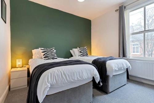 a bedroom with two beds and a green wall at Becky's House: Near Motor Point Arena with Free Parking in Nottingham