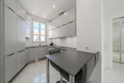 une cuisine avec des placards blancs et une table noire dans l'établissement Wdf 2 bedrooms heart of Cannes, à Cannes