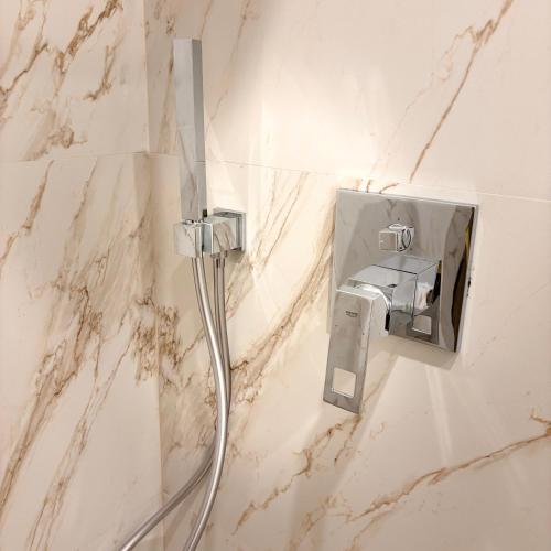 a shower head in a bathroom with marble walls at Hotel Clipa in Drobeta-Turnu Severin