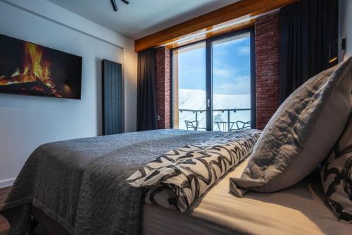 1 dormitorio con 1 cama con chimenea y ventana en Gudauri Mountain Views, en Gudauri