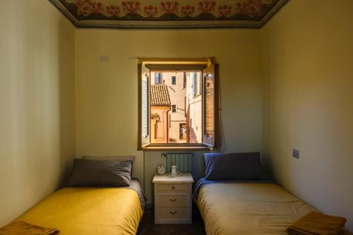 dwa łóżka w pokoju z oknem w obiekcie Appartamento compagnoni w mieście Macerata