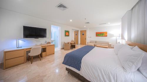 a bedroom with a bed and a desk with a television at Hotel Dann Carlton Barranquilla y Centro de Convenciones in Barranquilla