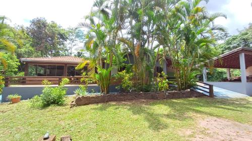 una casa con palmeras frente a un patio en Sítio Encontro das Águas Brotas, en Ibirapuera