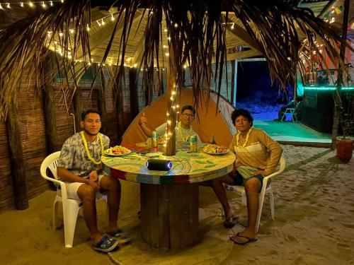 four people sitting around a table in a tent at Pepon Surf Camp in Máncora