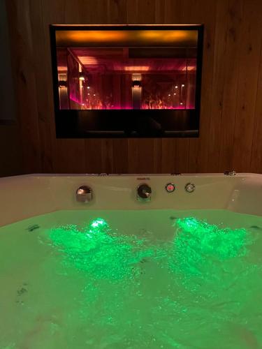 a bath tub filled with green water with a window at Hotel Adler in Oberstaufen