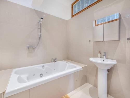 a white bathroom with a sink and a bath tub at Firs Retreat in Balderton