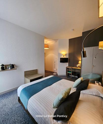 a hotel room with a large bed with pillows at Hôtel Le Rohan Charme et Caractère in Pontivy