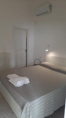 a white bedroom with two beds with white sheets at Il Porticato - Affittacamere in Paola
