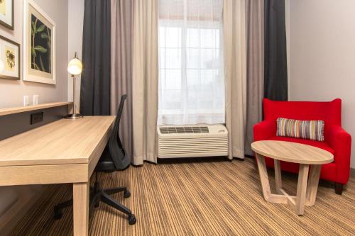 a room with a red chair and a desk and a window at Country Inn & Suites by Radisson, Rapid City, SD in Rapid City