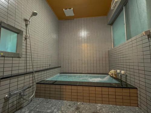 Baño con jacuzzi y ventana en Eimiya Ryokan - Vacation STAY 36263v, en Amakusa