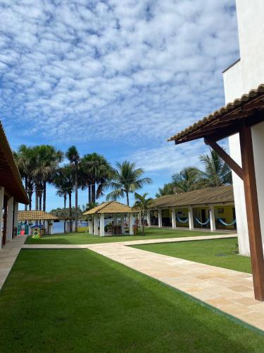 a resort with a lawn and palm trees in the background at Lagoa do Cassó - Pousada Porto do Cajú in Caçozinho