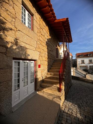 a brick building with a white door and stairs at Casa da Vila - Apartamento rés chão in Alpedrinha