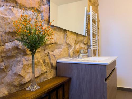 baño con lavabo y jarrón con flores en Casa Rural Claudia, en Puigmoreno