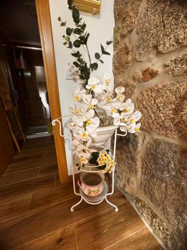 a white cart with flowers on it next to a wall at Casa da Vila - Apartamento rés chão in Alpedrinha
