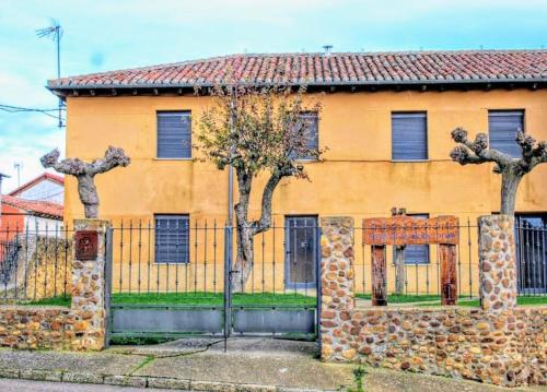 un bâtiment jaune avec des arbres devant une clôture dans l'établissement CASA LA VILLA, à Villamartín de Don Sancho