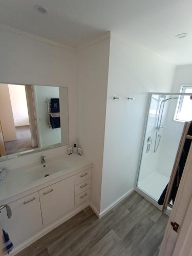 a bathroom with a sink and a shower with a mirror at Beaches Motel in Waihi Beach