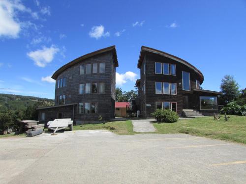 a large wooden house with a bench in front of it at Lodge Cumbres de Chiloe in Castro