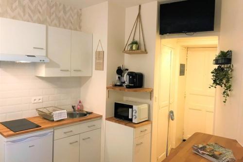 une petite cuisine avec un évier et un micro-ondes dans l'établissement L'Escale-Cosy appart hypercentre et au calme, à Nantes