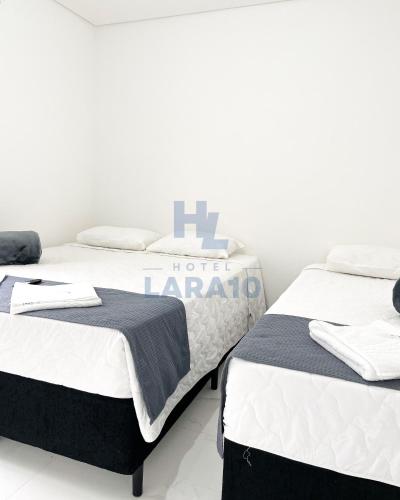 two beds sitting next to each other in a room at Hotel Lara 10 Curitiba in Curitiba
