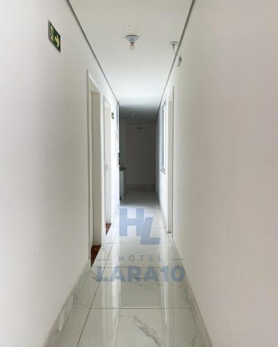 a corridor of an office building with white walls and tile floors at Hotel Lara 10 Curitiba in Curitiba
