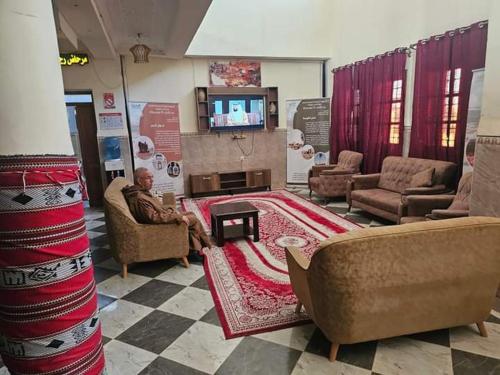 a man sitting on a couch in a living room at بيت الشباب 22 فبراير ورقلة in Bordj Lutaud