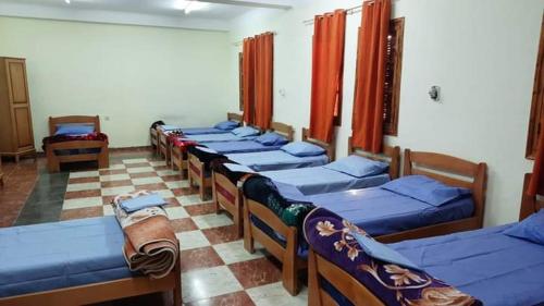 una habitación con una fila de camas en una habitación en بيت الشباب 22 فبراير ورقلة, en Bordj Lutaud
