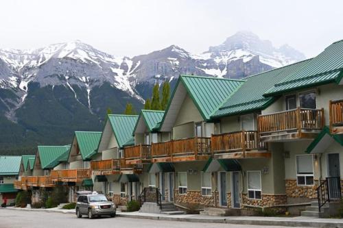 a row of houses with mountains in the background at Banff Woods lodge in Canmore