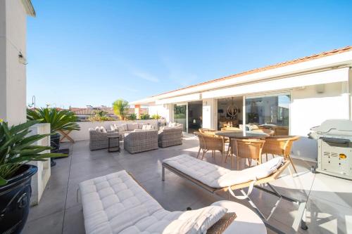Elle comprend une terrasse dotée d'un mobilier blanc, d'une table et de chaises. dans l'établissement Cannes Luxury Rental - Pretty 3 bedroom apartment to rent with 50m terrace, à Cannes