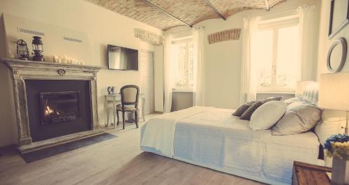 a white bedroom with a bed and a fireplace at Langhe Country House in Neive