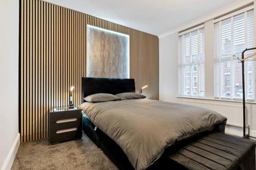 a bedroom with a large bed with a wooden wall at Liz's 4 Bed House: Close to the Motor Point Arena in Nottingham