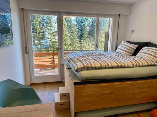 1 dormitorio con 1 cama y puerta corredera de cristal en Studio Serenity, 4 min walk to ski!, en Crans-Montana
