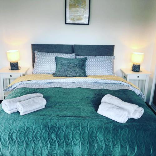 Un dormitorio con una cama verde con toallas. en Bay View Bungalow Benllech, 5 Min Walk from Beach en Benllech
