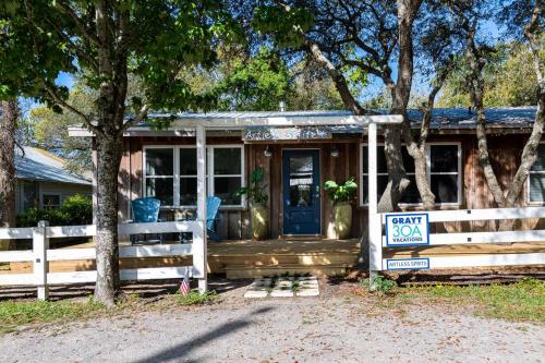 a small house with a fence and a blue door at Artless Sprite in Santa Rosa Beach