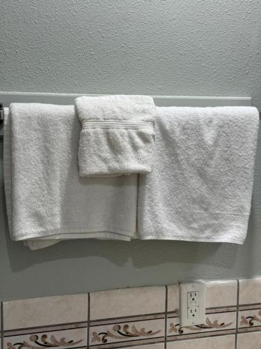 2 toallas blancas colgando de un toallero en el baño en La Cienega Inn Motel en Los Ángeles
