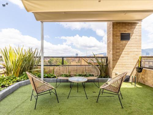 a patio with two chairs and a table on the grass at Kubik apartments in Exclusive Virrey in Bogotá