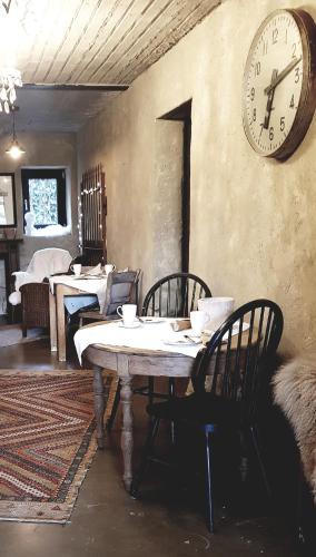 a dining room with a table and a clock on the wall at Le Lodge des Flâneurs in Vielsalm