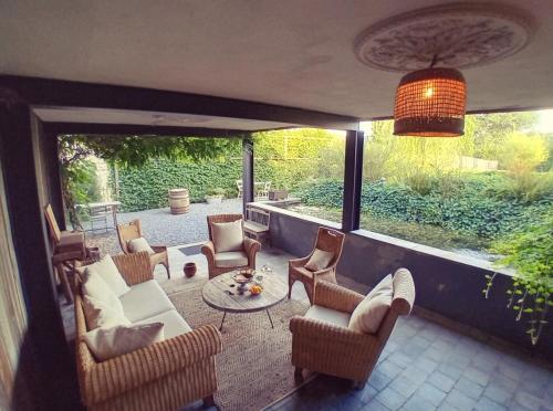 un porche cubierto con sillas y mesa en Le Lodge des Flâneurs, en Vielsalm