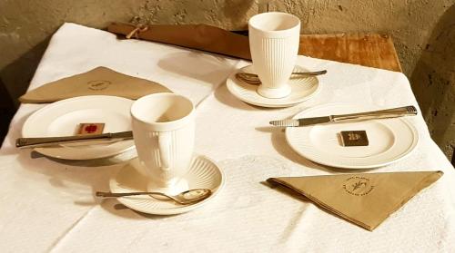 a table topped with white plates and cups and silverware at Le Lodge des Flâneurs in Vielsalm
