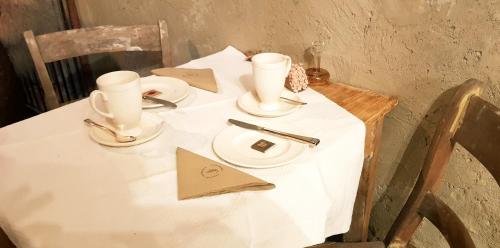 Una mesa blanca con dos tazas y platos. en Le Lodge des Flâneurs, en Vielsalm