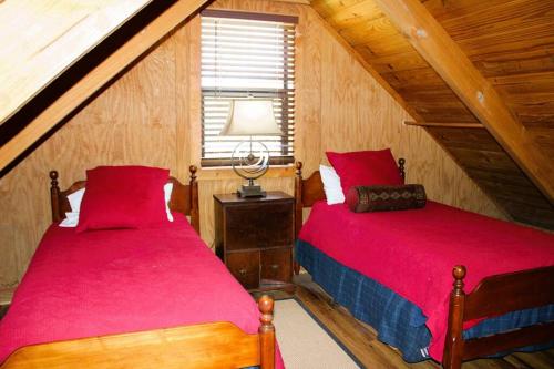 2 Betten in einem Schlafzimmer im Dachgeschoss mit roter Bettwäsche in der Unterkunft Hell Creek Cabin on the White River 