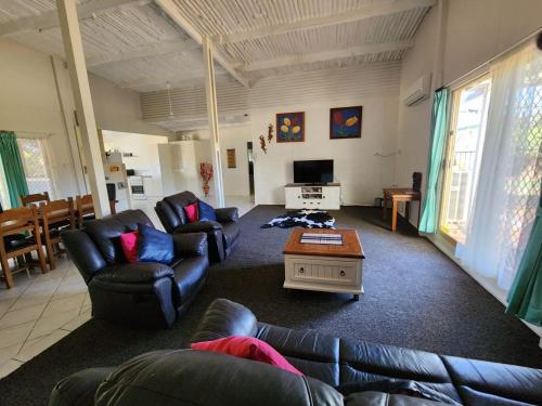 a living room with leather couches and a tv at Country Retreat The Blue Cottage in Gingin