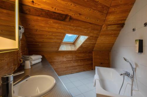 a bathroom with a wooden ceiling with a tub and a sink at Campanile Annecy Centre - Gare in Annecy